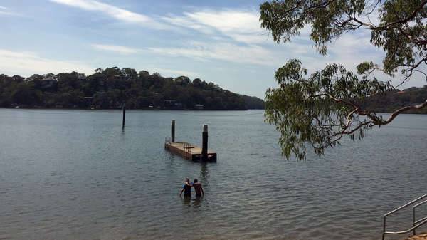 Two boys standing in the water in the Georges River about to swim