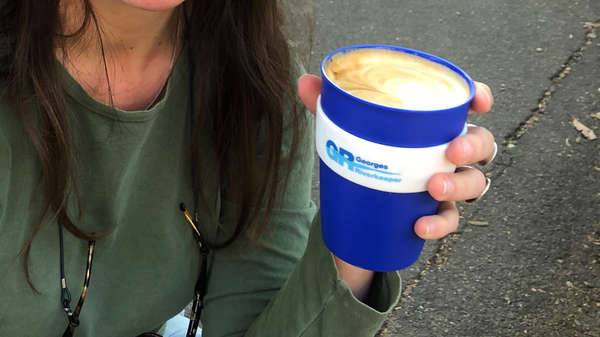 woman with Georges Riverkeeper branded reuseable coffee cup