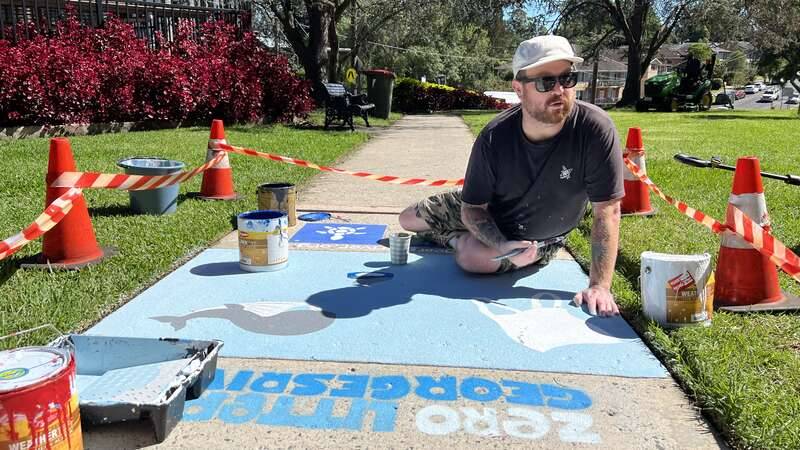 Corey Nichols, aka Born Ready Art, painting footpath art for the Zero Litter In Georges River project