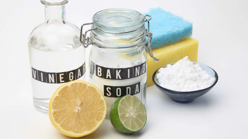 natural cleaning products in glass containers, including vinegar and baking soda, with salt and citrus