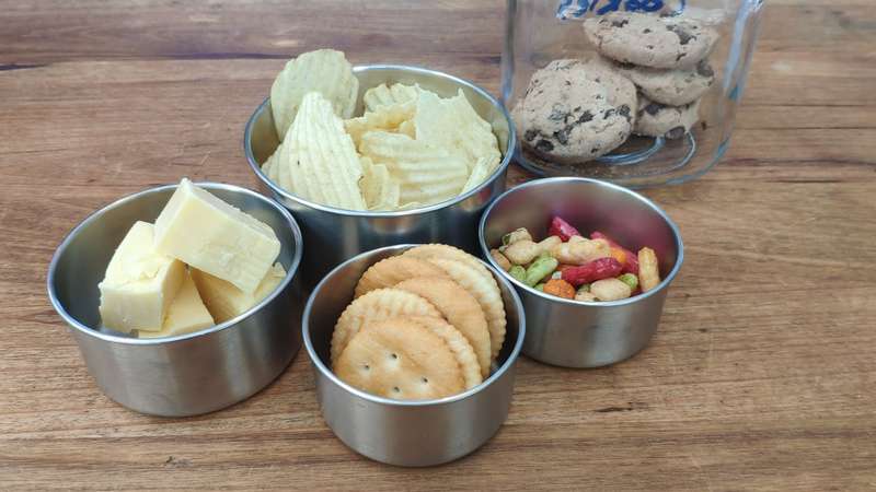 small containers containing snacks like chips, cheese, biscuits and nuts that have been decanted from bulk container