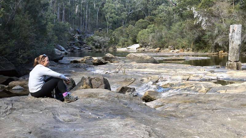 Female bushwalker sits admiring the Georges River at Freres Crossing, Campbelltown