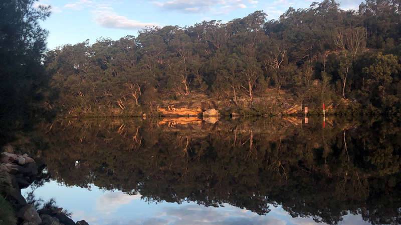 view of the bushland and sandstone banks of the Georges River with reflection in the water